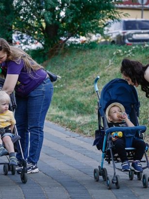 a woman pushing a stroller with two children in it