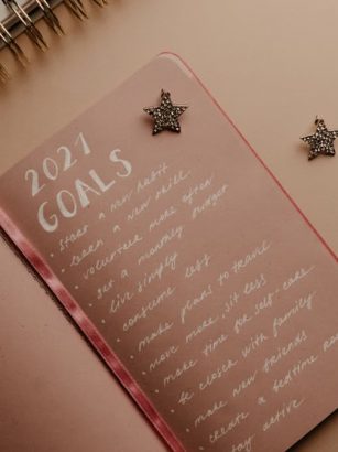 Top view of a 2021 goals notebook with handwritten list and star decorations, ideal for planning inspiration.