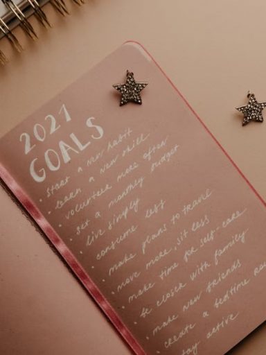 Top view of a 2021 goals notebook with handwritten list and star decorations, ideal for planning inspiration.